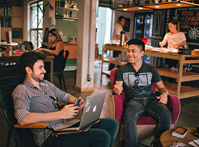 Two people with laptops smiling comunicating about a project