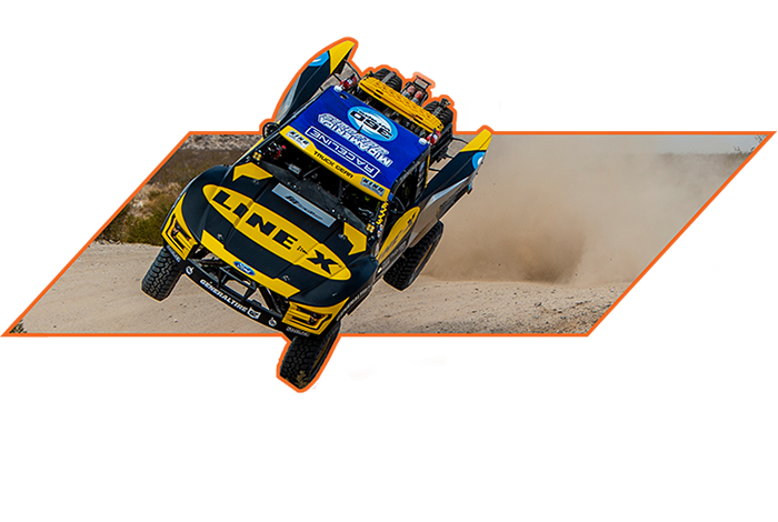 Off-road racing truck mid-jump on rugged terrain, featuring LINE-X branding—ideal for showcasing high-performance automotive accessories and motorsport action.